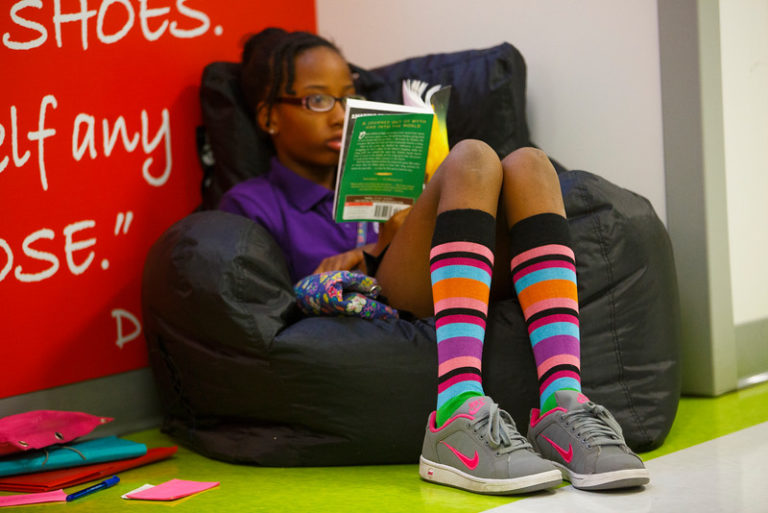 Young, female African American student with colorful socks sitting on a bean bag chair.