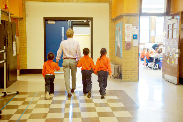 Man walking holding students' hands