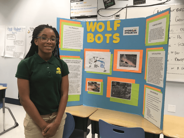 A student stands with her presentation