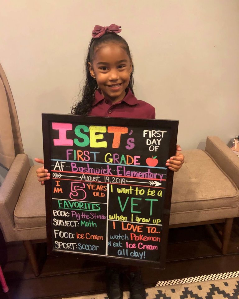 Iset holding up a blackboard with her name