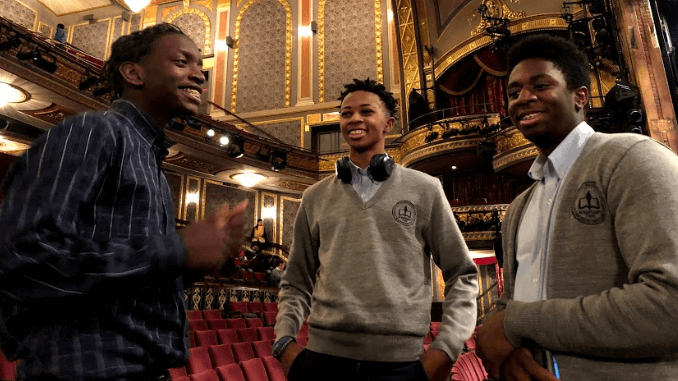 Three students standing together in a theater