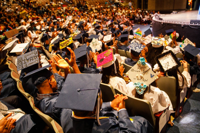 Students wearing caps and gowns in an auditorium