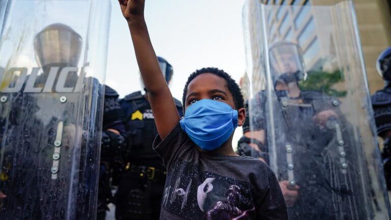 A young boy raises his fist for a photo by a family friend during a demonstration in Atlanta.